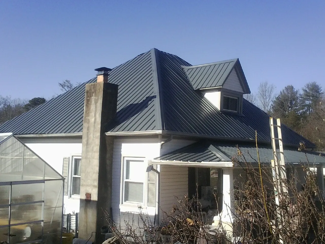 Dark blue standing seam metal roof on a white farmhouse with dormer — Slate & Tile Roof Repair by Roofing Brothers in Antrim