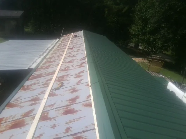 Old rusted panels beside newly installed green metal roofing — Wind Damage Roof Repair by Roofing Brothers in Antrim