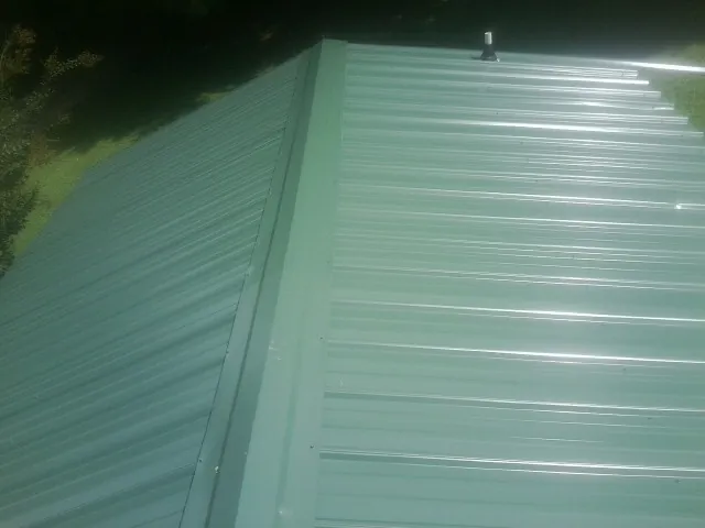 New green metal panels meeting at the ridge of a roof — Flat Roof Repair work by our crew in Antrim