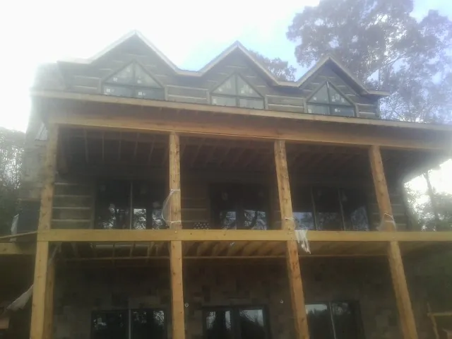 Dormers and porch framing on a large log home under construction — Roof Coating work by our crew in Antrim