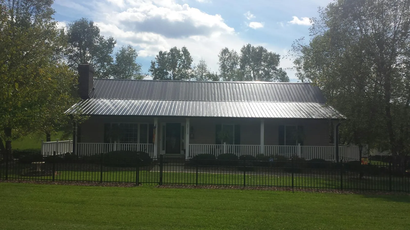 Gray metal roof on a brick ranch with a full width front porch — Gutter Guard Installation work by our crew in Antrim