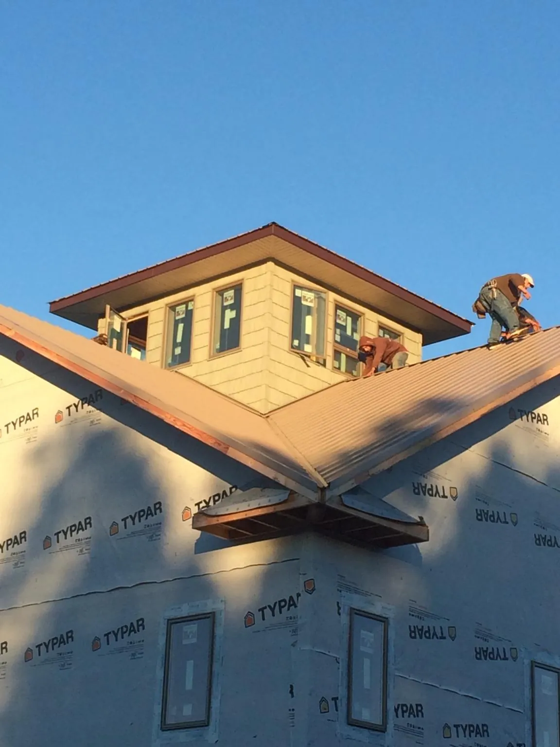 Roofers working around a rooftop cupola on a new metal roof at sunset — Roof Waterproofing in Antrim by Roofing Brothers